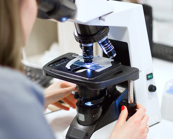 Technician looking into microscope.